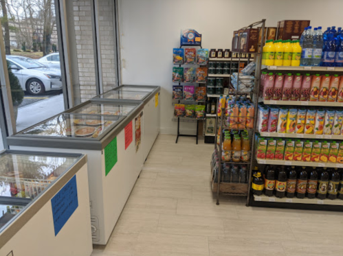 A store interior featuring freezers on the left and shelves stocked with drinks and snacks on the right.