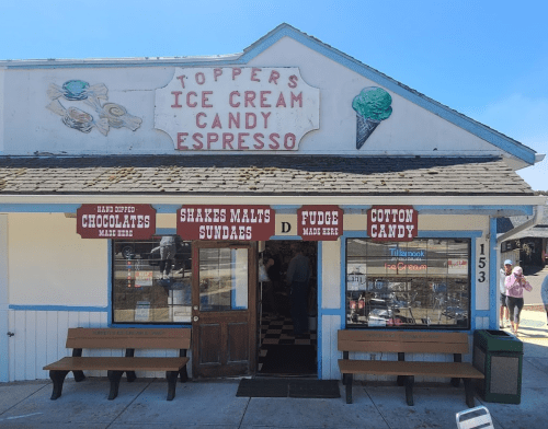 Exterior of Toppers Ice Cream Candy Espresso shop, featuring a sign and colorful window displays.