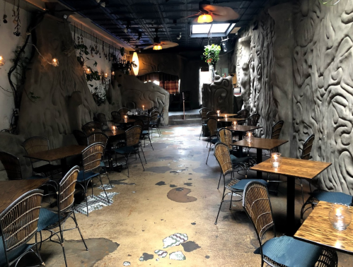 A unique restaurant interior with textured walls, wooden tables, and wicker chairs, creating an inviting atmosphere.