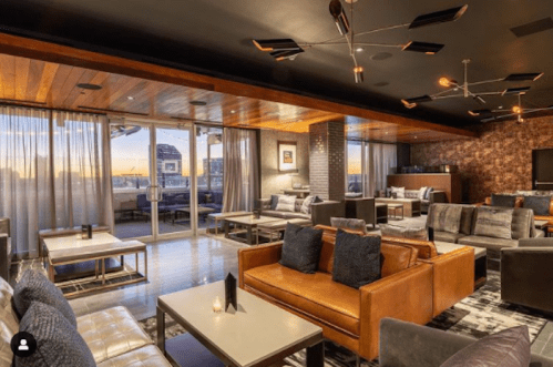 Modern lounge with stylish seating, large windows, and a warm ambiance, featuring a sunset view.