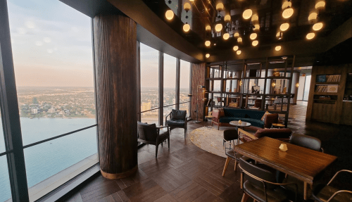 Modern lounge with large windows, offering a panoramic view of the city and lake, featuring stylish furniture and decor.