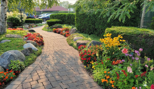 A winding stone path surrounded by vibrant flowers and greenery, leading through a beautifully landscaped garden.