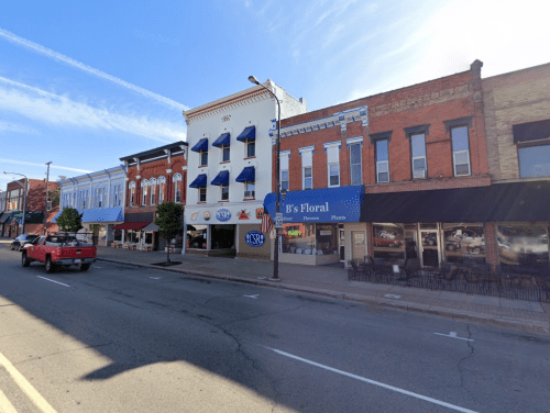 A charming street view featuring colorful storefronts, blue awnings, and a clear blue sky.
