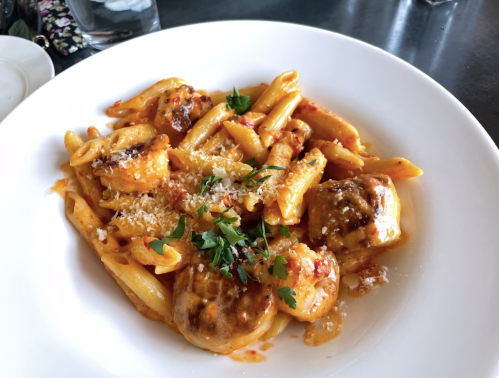 A plate of pasta with shrimp, penne, and a rich tomato sauce, garnished with parsley and grated cheese.