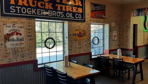Interior of a diner with wooden tables, dollar bills on the walls, and large windows letting in natural light.