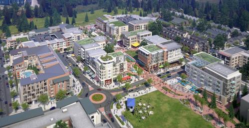 Aerial view of a modern mixed-use development with shops, apartments, and green spaces, surrounded by trees.