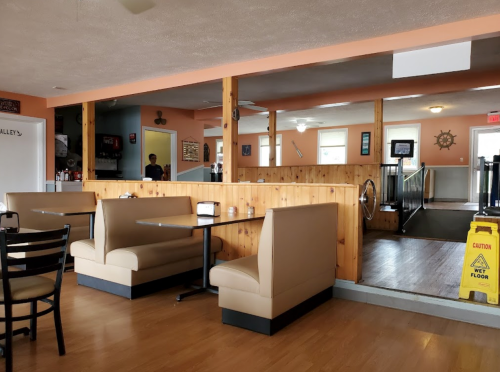 Interior of a casual restaurant featuring booths, wooden paneling, and a caution sign on the floor.