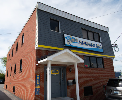 A brick building with a gray roof and a sign that reads "Big Kahuna's Hawaiian BBQ" above the entrance.
