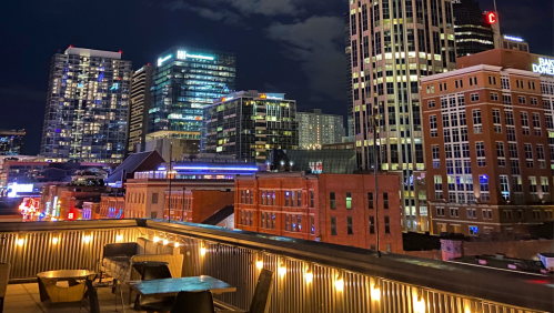 City skyline at night with illuminated buildings and rooftops, showcasing a vibrant urban atmosphere.
