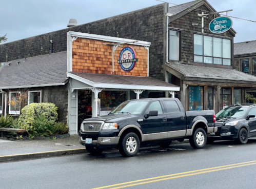 A gray pickup truck parked in front of a rustic storefront with a circular sign and a spa above it.