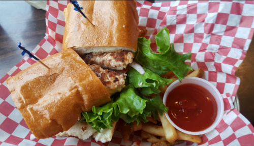 A sandwich with two patties, lettuce, and a side of fries and ketchup, served in a red-checkered basket.