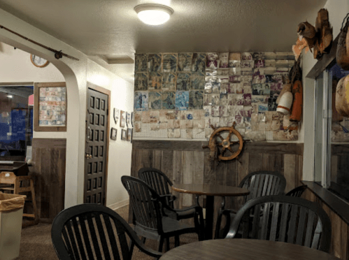 Cozy interior of a café with wooden walls, circular tables, and a wall covered in vintage photos.