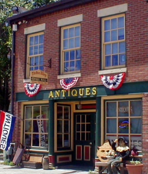 A charming antique shop with red brick exterior, bunting decorations, and a welcoming entrance.