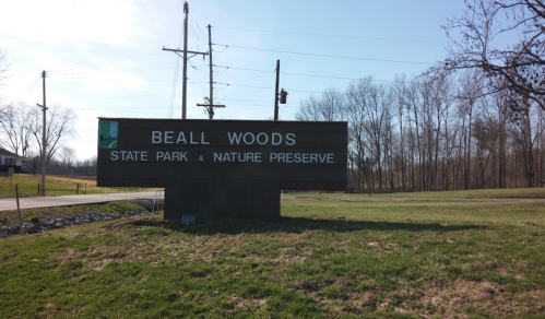 Sign for Beall Woods State Park & Nature Preserve, surrounded by trees and open grassland.