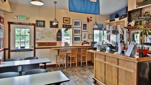 Cozy interior of a pub with wooden bar, seating, maps on the walls, and a sign for "Free Beer."