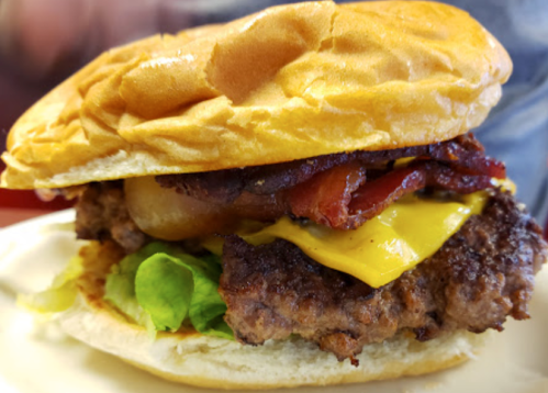 A juicy cheeseburger with bacon, lettuce, and a soft bun, served on a plate.