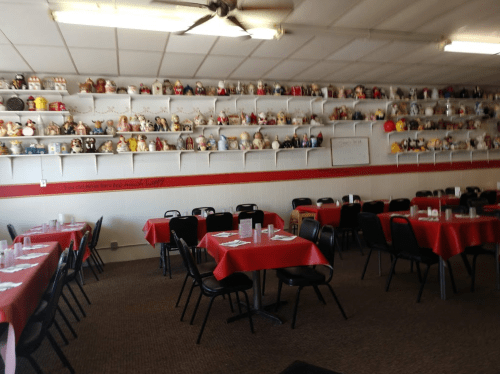 A cozy restaurant with red tablecloths and shelves lined with various decorative dolls and figurines.