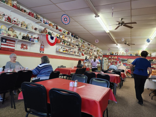 A cozy restaurant interior with red tablecloths, shelves filled with collectibles, and patrons enjoying their meals.