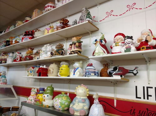 A display of various decorative ceramic items, including holiday-themed figures, on shelves against a white wall.
