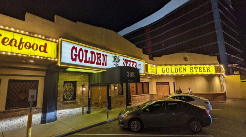 Exterior of the Golden Steer restaurant at night, featuring bright signage and a parked car in front.