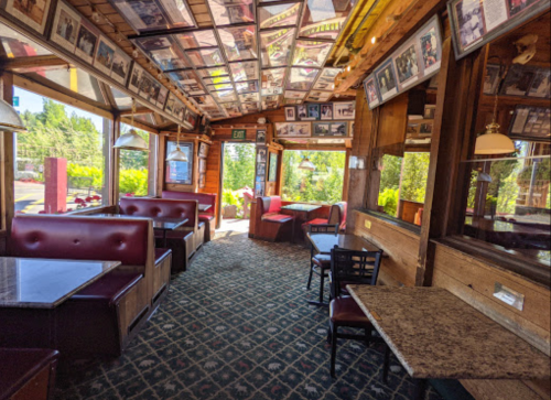 Cozy restaurant interior with wooden decor, framed photos on the ceiling, and booths along the walls.