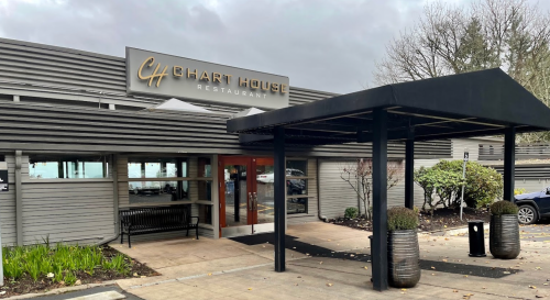 Exterior of Chart House Restaurant featuring a modern entrance and covered walkway, surrounded by greenery.