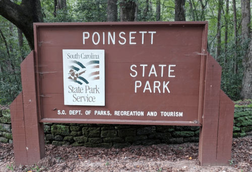 Sign for Poinsett State Park in South Carolina, featuring the state park service logo and information about recreation and tourism.