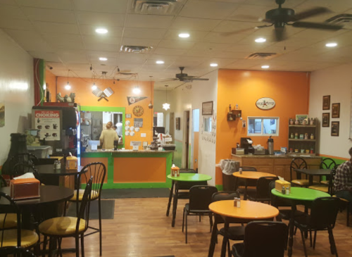 Cozy restaurant interior with colorful walls, tables, and a counter area. A customer is at the register.