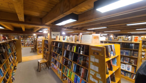 A cozy bookstore interior with wooden shelves filled with books and warm lighting, inviting reading spaces visible.