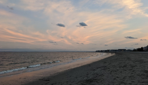 A serene beach at sunset, with gentle waves and colorful clouds in the sky.