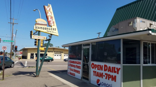 A retro hamburger stand with a large sign, featuring "Val's Hamburgers" and open daily from 11 AM to 7 PM.
