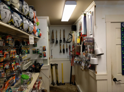 A well-organized store aisle featuring sports balls, tools, and various hardware items on display.