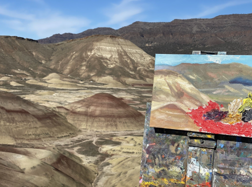 A painter's easel displays a colorful landscape painting against a backdrop of rugged hills and blue sky.