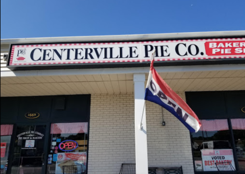Sign for Centerville Pie Co. with "OPEN" flag, showcasing a bakery and pie shop on a sunny day.