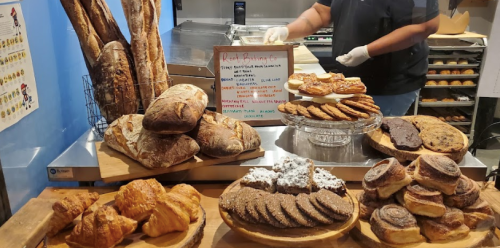 A display of various baked goods, including breads, pastries, and cookies, with a menu sign in the background.