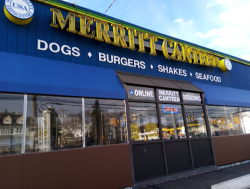 Exterior of Merritt Canteen, featuring signs for hot dogs, burgers, shakes, and seafood, with an "Open" sign visible.
