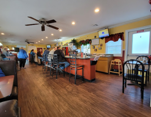 A cozy diner interior with patrons seated at the counter and tables, featuring warm lighting and a welcoming atmosphere.