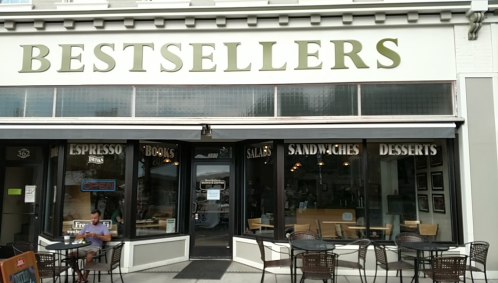 A café named "Bestsellers" with outdoor seating, offering espresso, books, salads, sandwiches, and desserts.