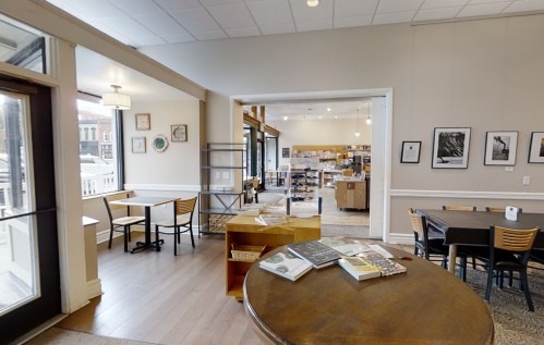 A cozy bookstore interior with tables, chairs, and shelves filled with books, featuring warm lighting and a welcoming atmosphere.