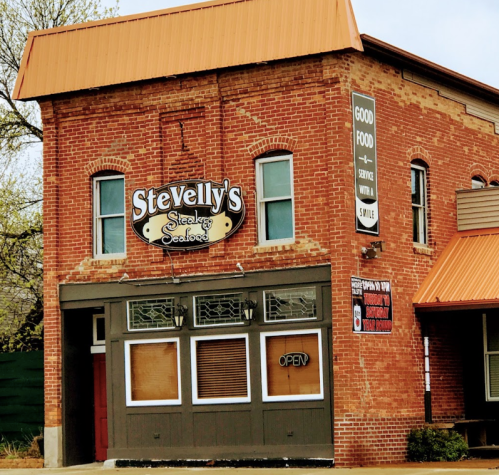 A brick building with an orange roof, featuring a sign for "Stevelly's Steak & Seafood" and an "OPEN" sign in the window.