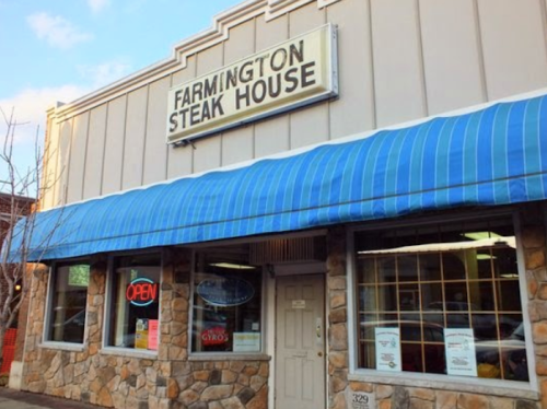 Exterior of Farmington Steak House with a blue awning, stone facade, and an "Open" sign in the window.