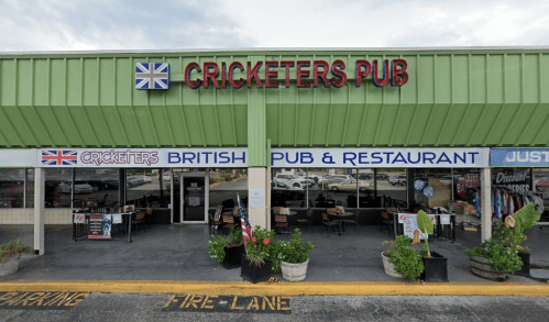 Exterior of Cricketers Pub, a British pub and restaurant, featuring a green awning and outdoor seating.