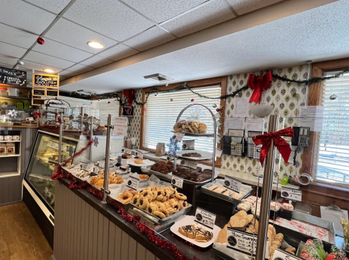 A cozy bakery display filled with various pastries and cookies, decorated for the holidays with festive accents.