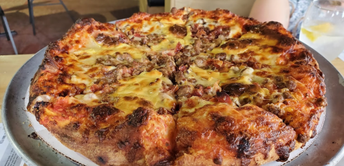A freshly baked pizza with a golden crust, topped with melted cheese and chunks of sausage.