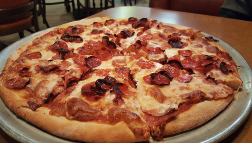 A freshly baked pizza topped with melted cheese and crispy pepperoni slices, served on a metal tray.