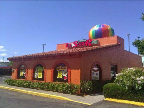 Colorful restaurant exterior with a large striped ball on the roof and vibrant signage promoting food specials.