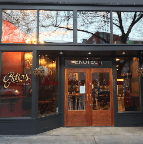Exterior of Esters Enoteca, featuring large glass windows, wooden doors, and a welcoming atmosphere.