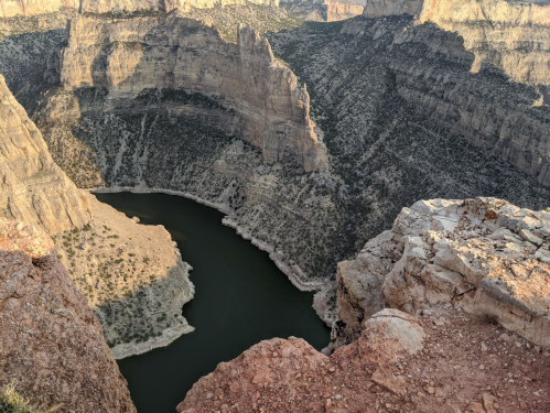 Aerial view of a winding river surrounded by steep, rocky cliffs in a canyon landscape.