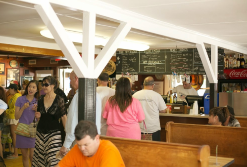 A busy diner scene with customers ordering at the counter and others seated at wooden booths.