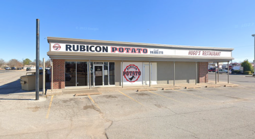 Exterior of Rubicon Potato restaurant, featuring a sign and large windows, with a clear blue sky in the background.